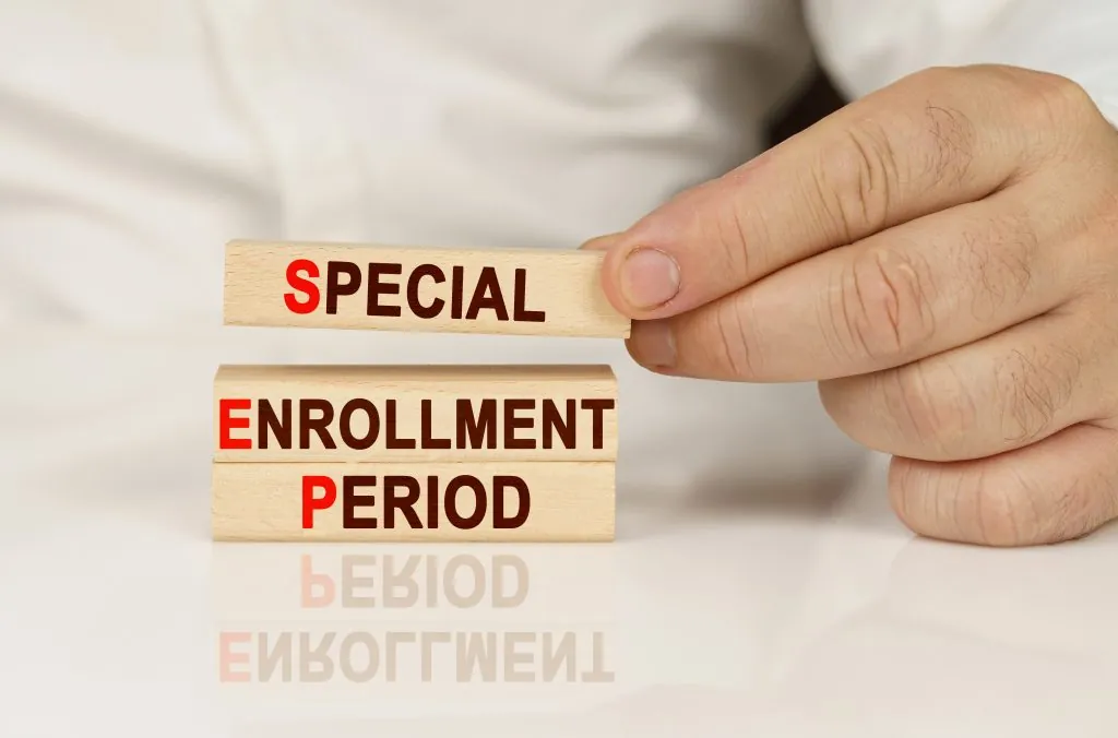 In the hands of a person and on a reflective surface are wooden blocks with the inscription - special enrollment period