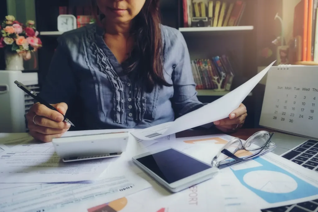 Accountant calculating taxes and personal income tax forms on desk, illustrating Income Reporting Impact Health Insurance.