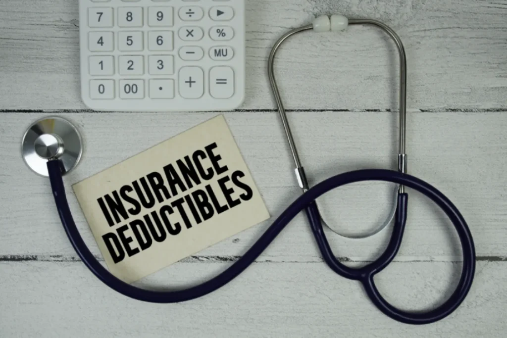 Stethoscope and calculator next to a card labeled Insurance Deductibles explaining health insurance deductible costs