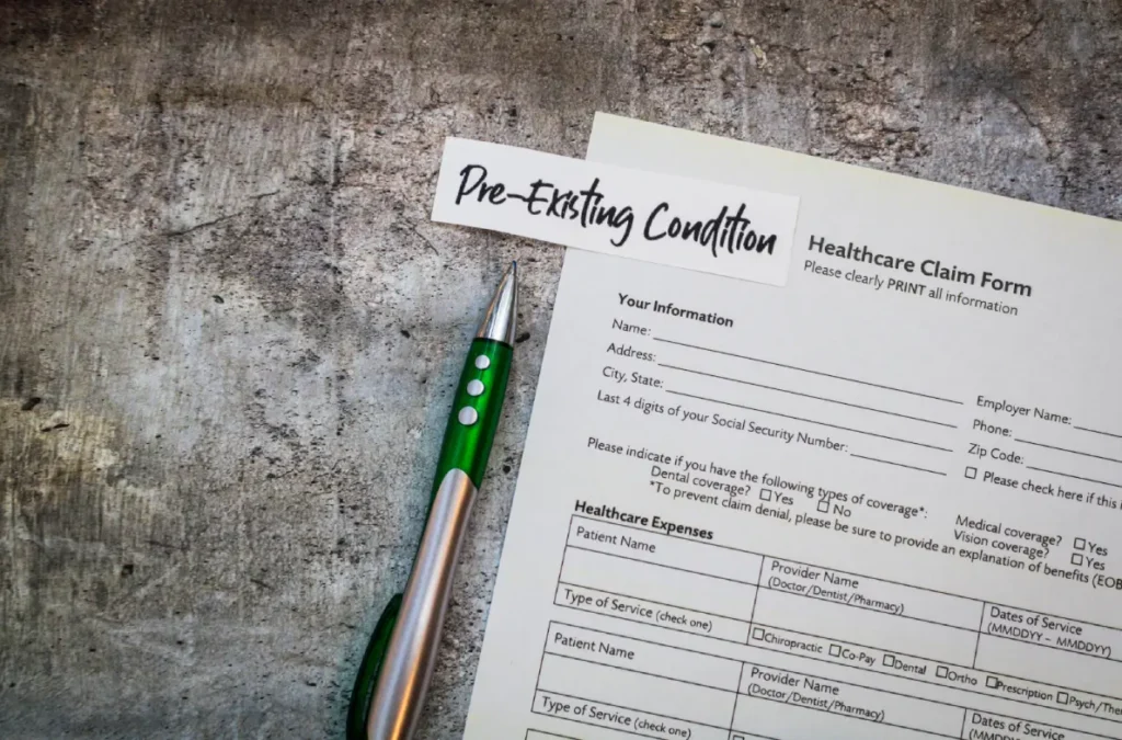 Healthcare claim form with a pre-existing conditions label and pen on a desk